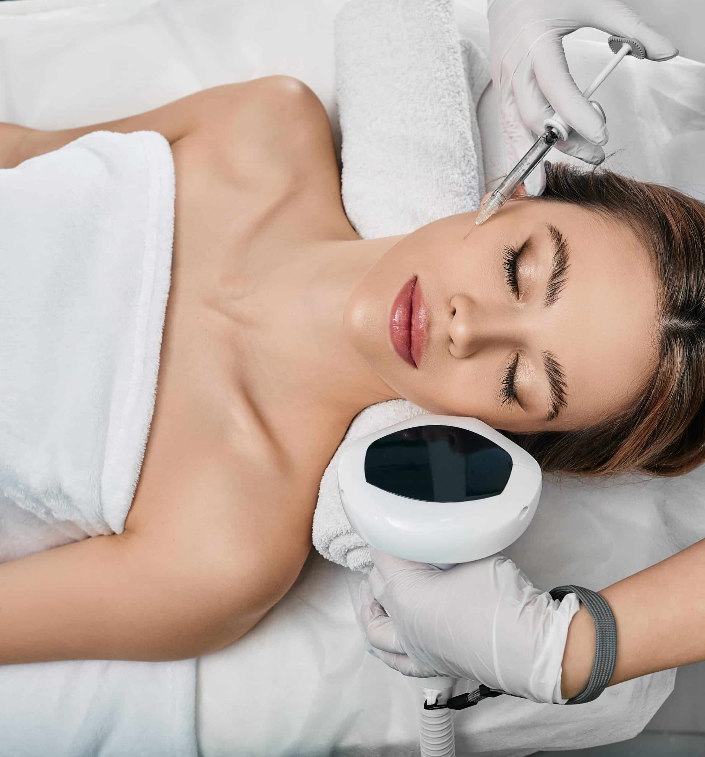 Photorejuvenation, rosacea treatment, removing brown spots and vascular mesh. Cosmetologist using IPL apparatus treats skin of female patient's face